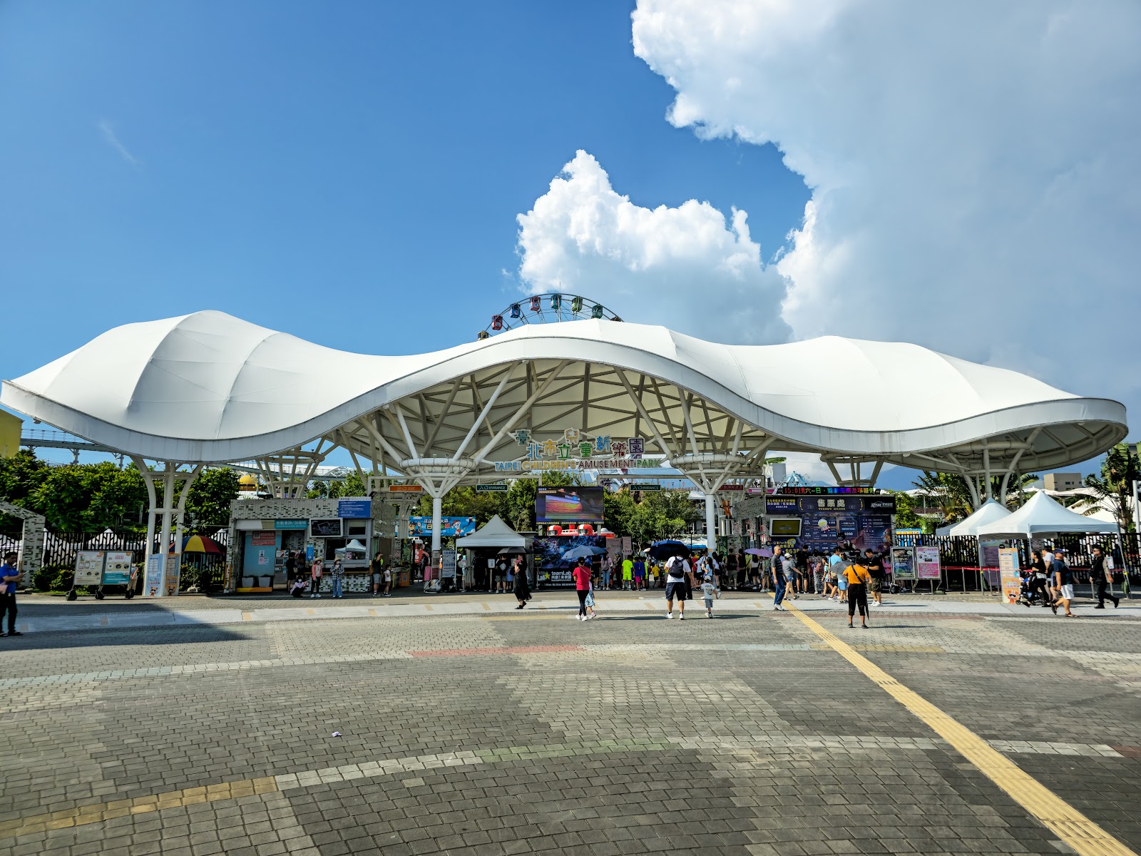 臺北市立兒童新樂園白色波浪造型入口廣場，遠方可見摩天輪