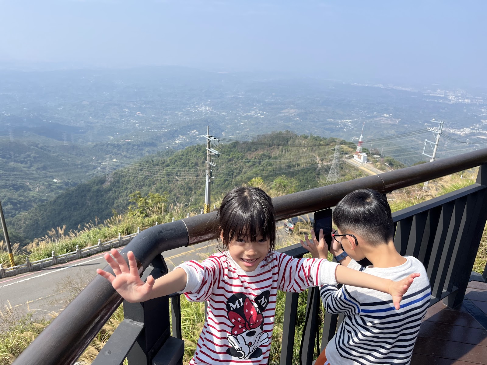 從太平雲梯高處俯瞰嘉義平原全景，蜿蜒山路，遠處城市藍天