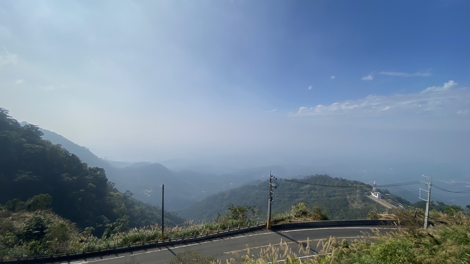 太平山區山路轉彎處眺望嘉義山巒，右側山頂白色塔狀建築，晨霧飄渺