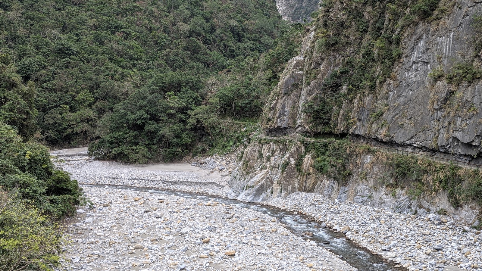 太魯閣立霧溪峽谷全景，大理石峭壁聳立，礫石河床蜿蜒清澈溪流，花蓮一日遊