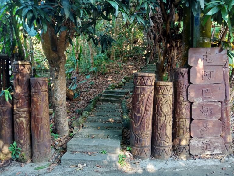 茶山部落屯阿巴娜步道入口，兩側矗立鄒族圖騰柱，後方鬱鬱蔥蔥的原始森林