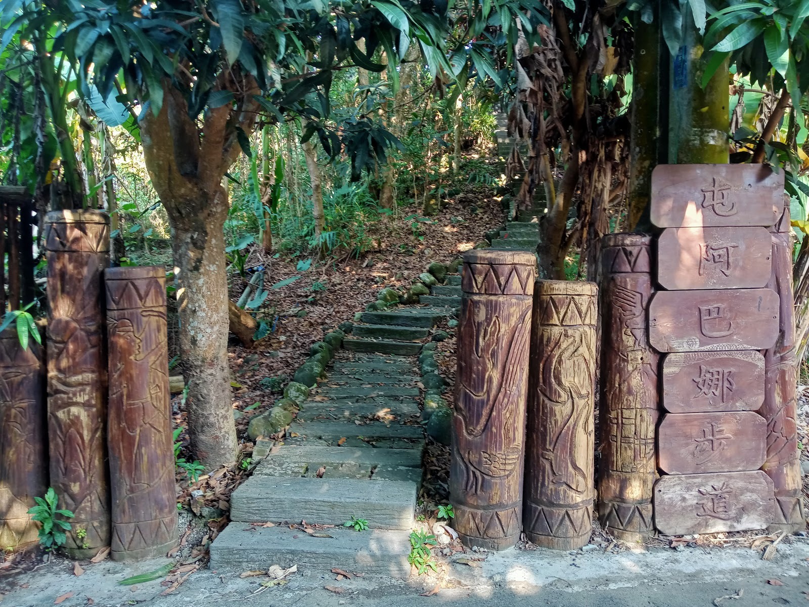 茶山部落屯阿巴娜步道入口，兩側矗立鄒族圖騰柱，後方鬱鬱蔥蔥的原始森林