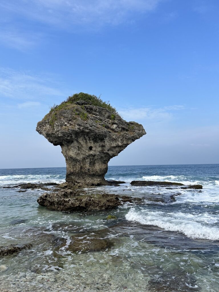小琉球花瓶石標誌性蕈狀礁岩，清澈海水拍打礁盤，藍天白雲
