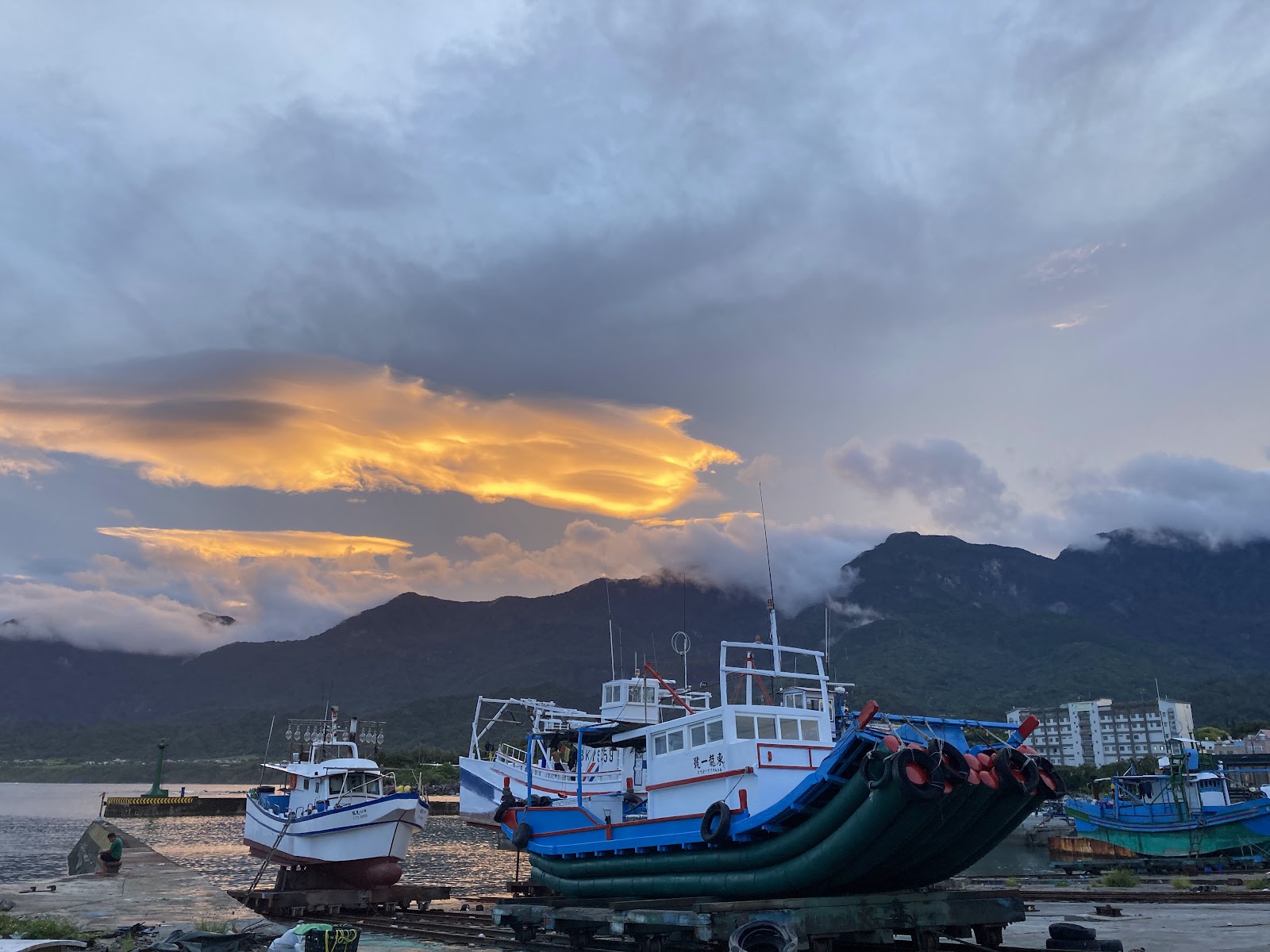 成功新港漁港黃昏漁船停泊，橘紅落日雲彩配山景，海洋之眼台東