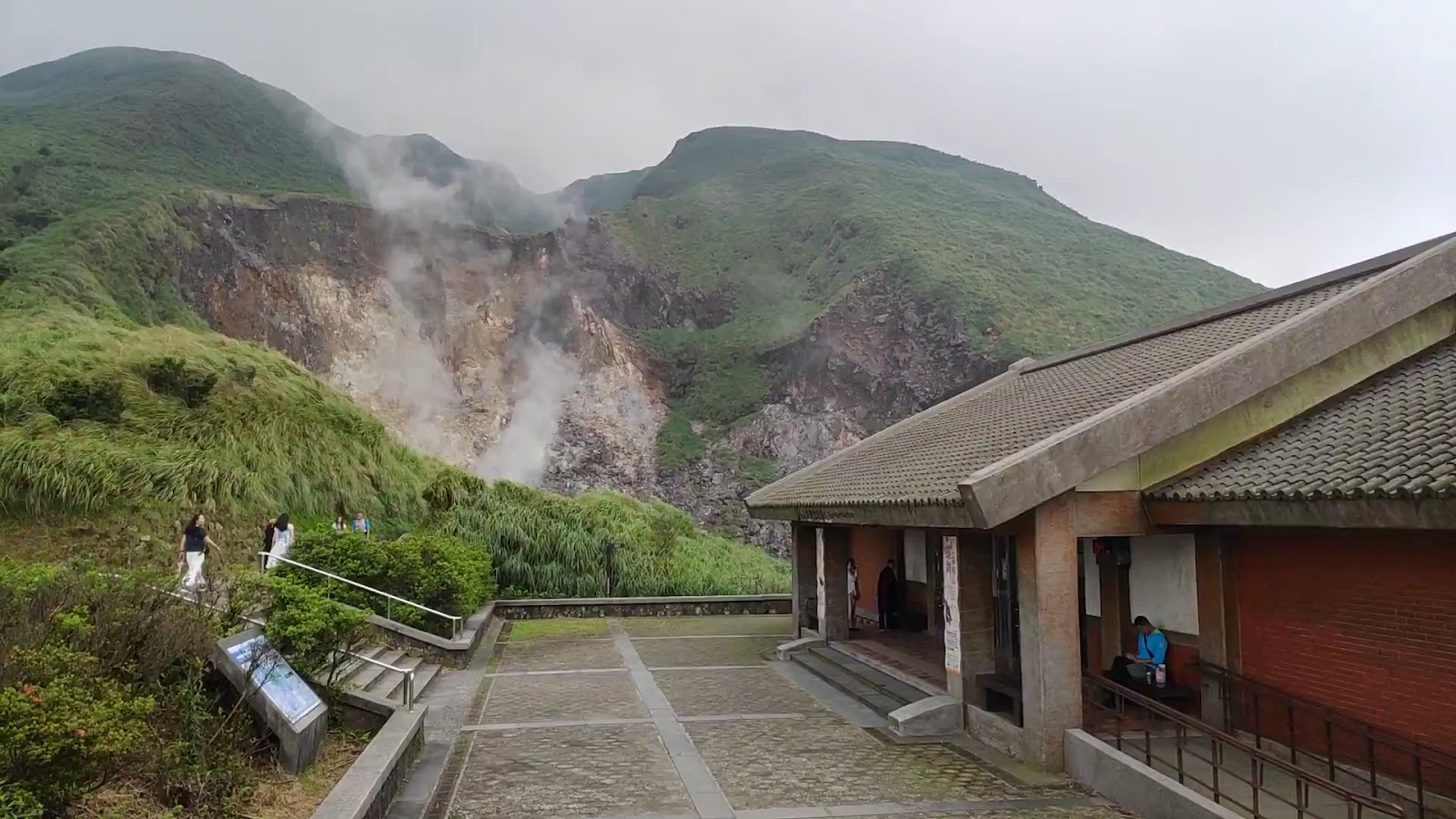 小油坑服務站建築陰天霧氣，步道遊客前行