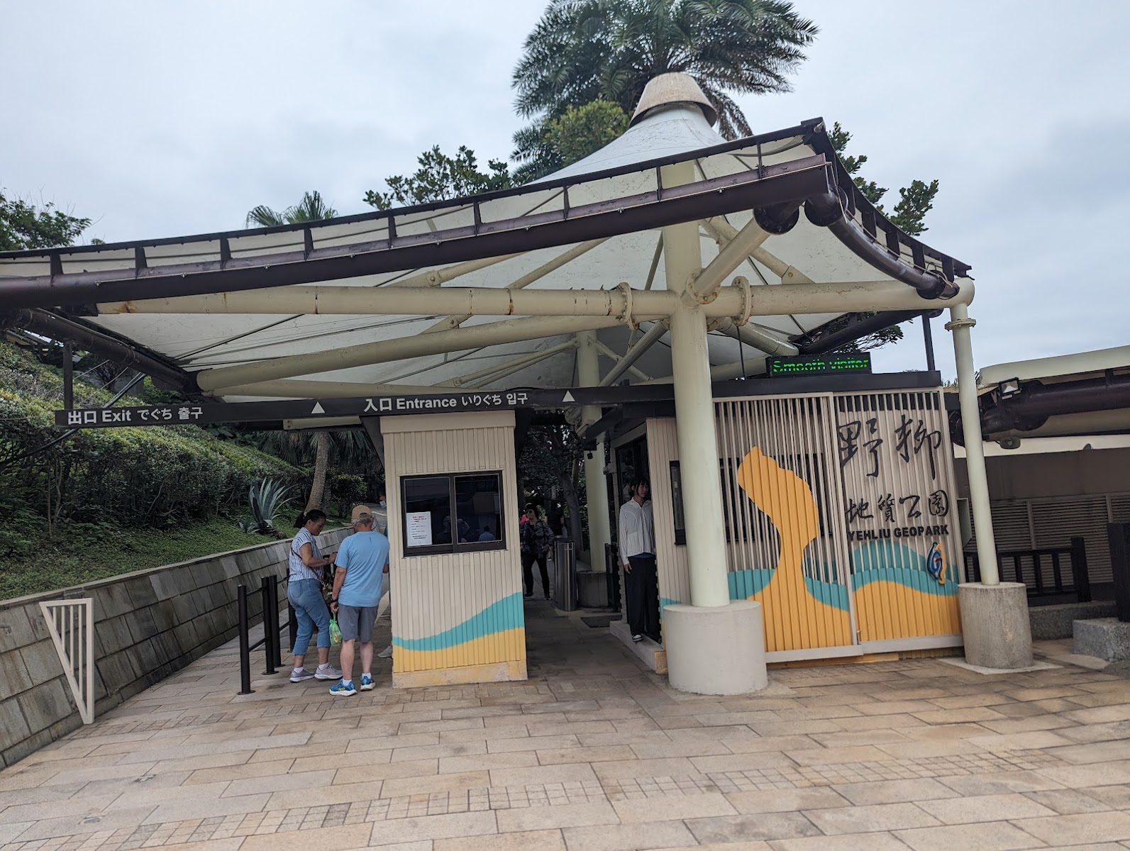 野柳地質公園售票入口建築,木質圓柱,多語言標示,遊客排隊購票