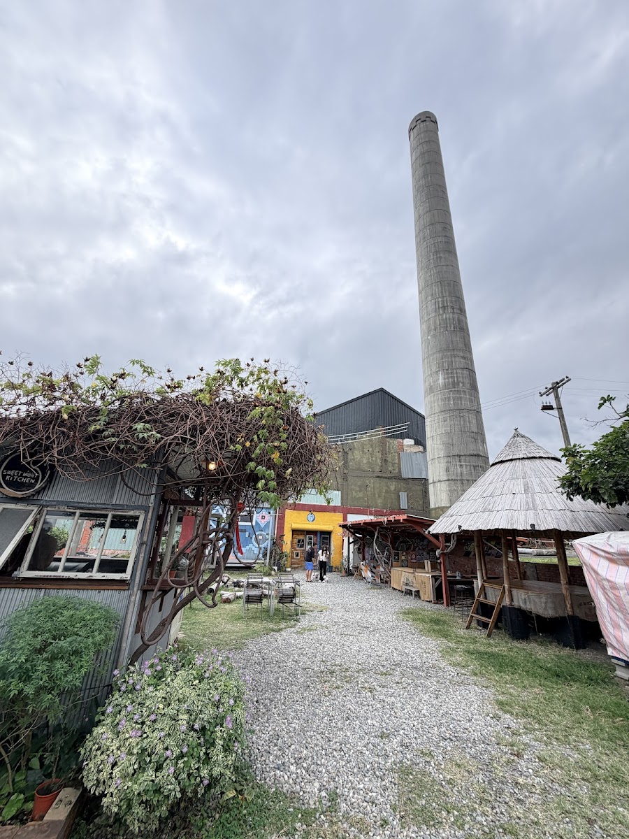都蘭糖廠標誌性白色大煙囪聳立,前方是文創市集攤位與咖啡屋棚架