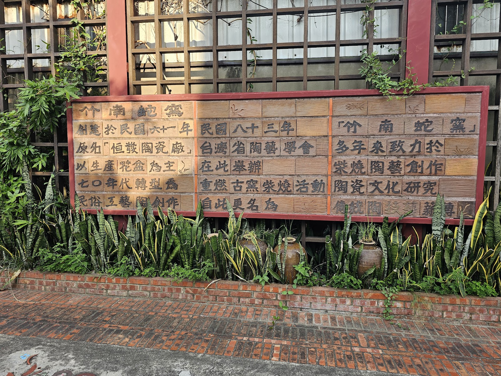 竹南蛇窯歷史建築歷史說明牌，紅色木框內有陶磚文字介紹創立沿革