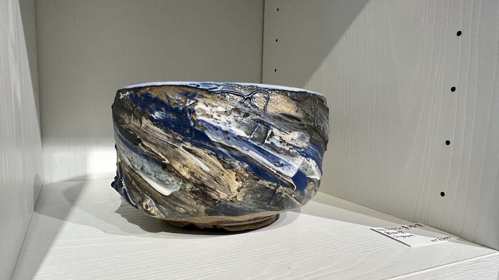 竹南蛇窯陶藝展品藍釉陶碗，展示於白色展架上