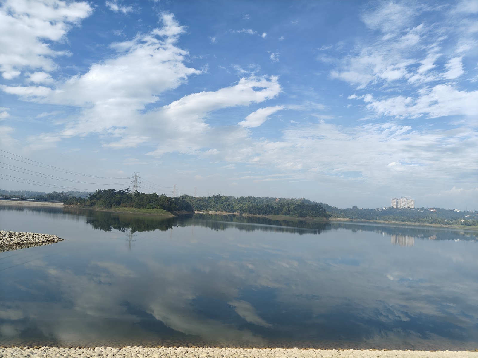 仁義潭廣角湖面倒影，電塔與山坡遠景