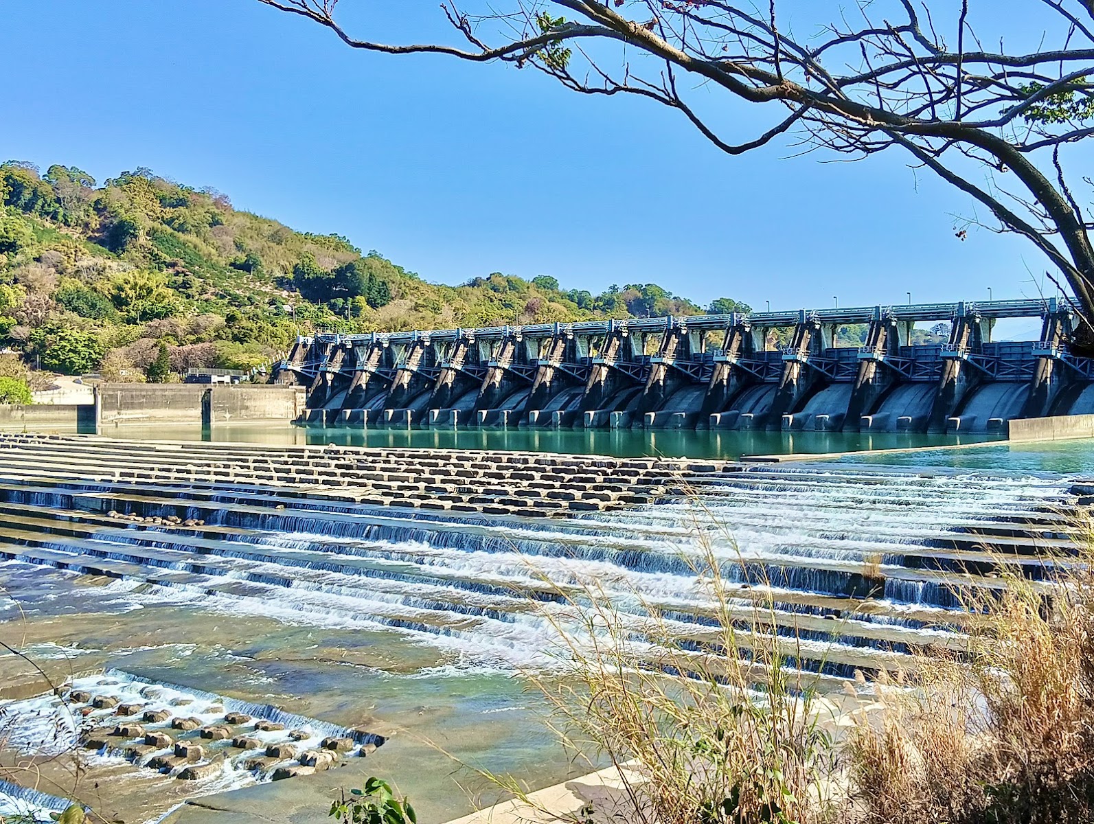 石岡水壩十二道弧形排砂閘門全景，晴日藍天碧水，台中石岡一日遊必訪景點