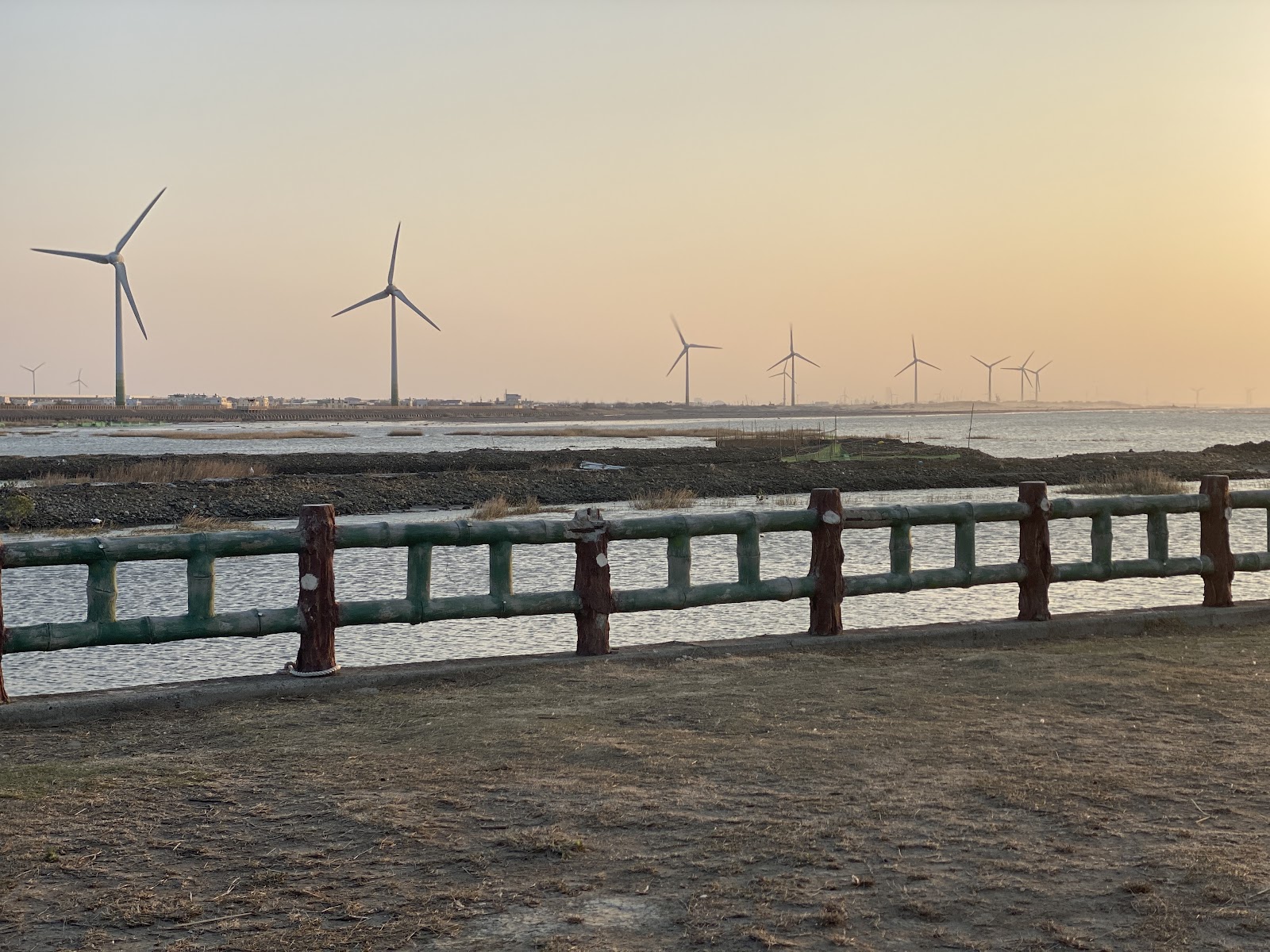 溫寮漁港夕陽黃昏漁港木欄杆遠處風車群景色