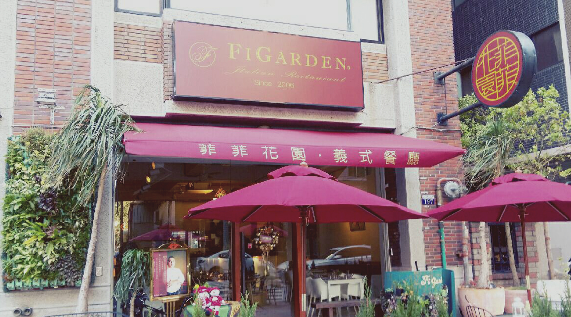 這張圖片主要顯示一家名為菲菲花園的義式餐廳門口，有紅色的遮陽傘、門口擺設植物、招牌及裝飾，整體風格溫馨且充滿綠意。圖片未見浮水印。