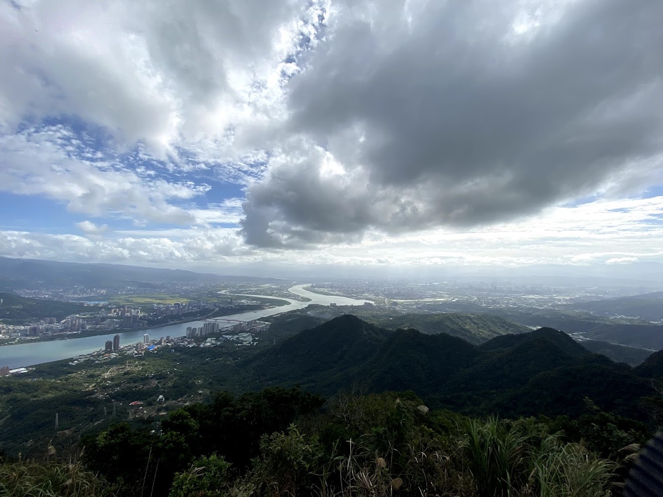 廣闊山景與河流交會，遠方可見都市建物