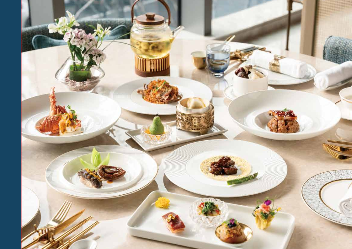 這張圖片展示一桌精緻高級的中式料理，包括海鮮、米飯、甜點和多樣小菜，搭配金色餐具與花茶壺，環境優雅，還有花藝擺設，適合高檔用餐。圖片未見浮水印。