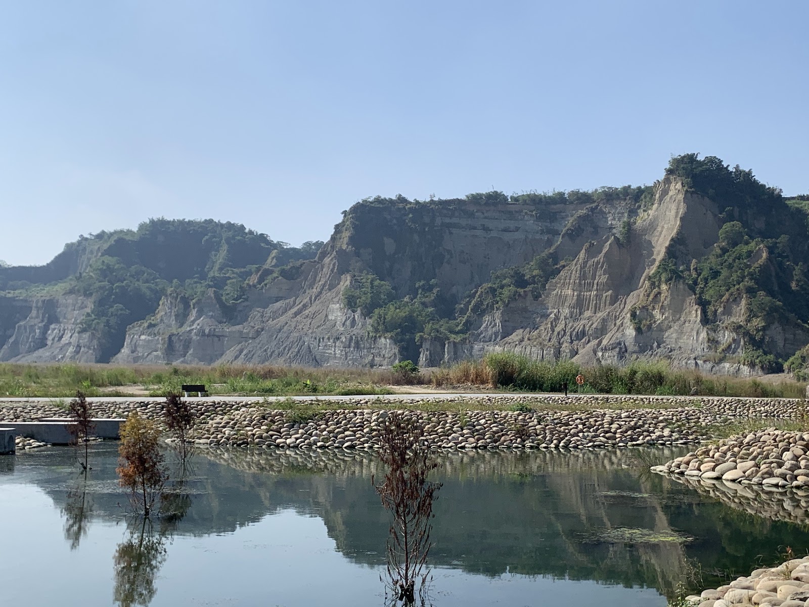 台東達仁鄉南田海岸親水公園鵝卵石圍繞的反射水池,背景灰白侵蝕山壁