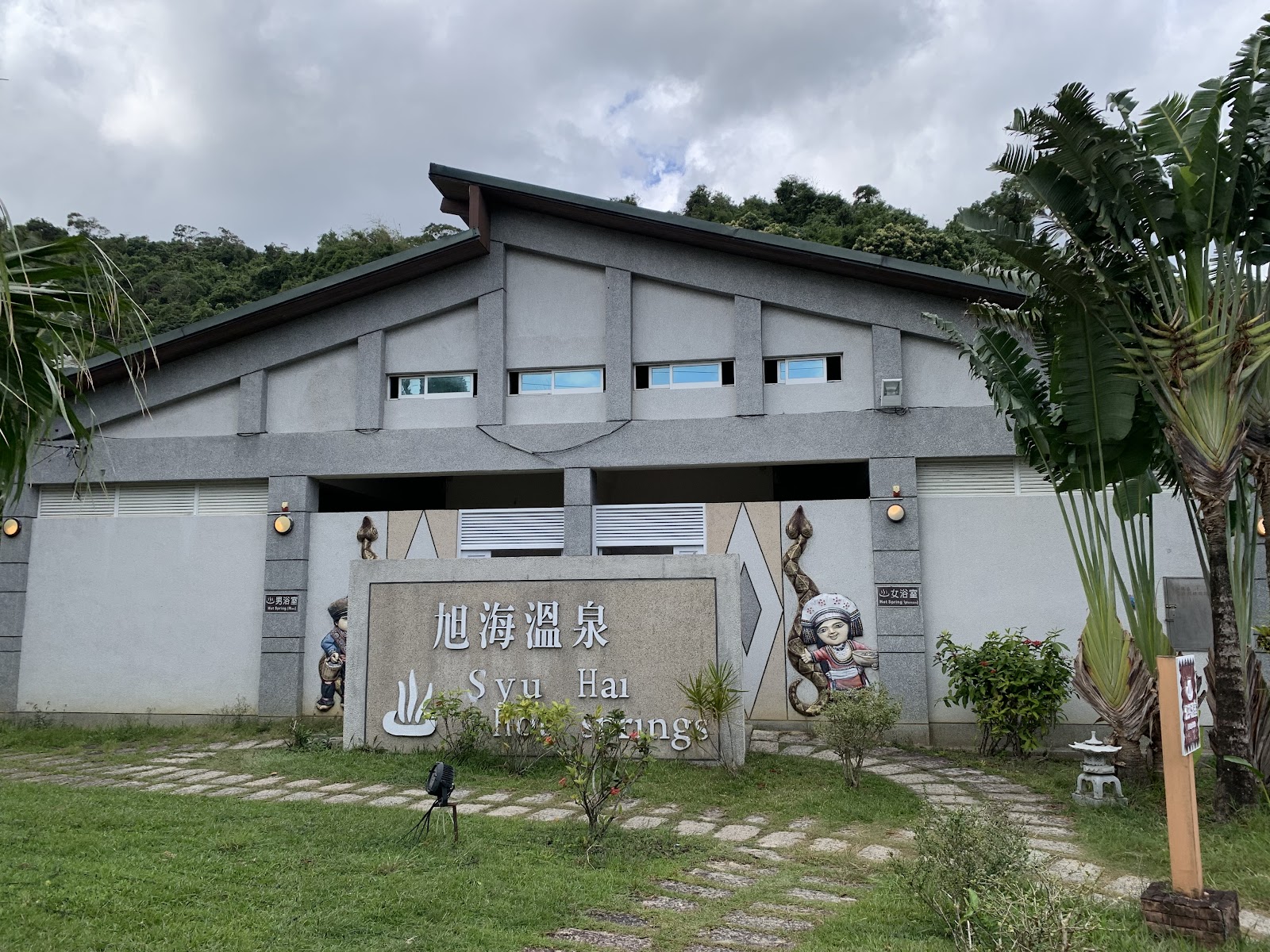 旭海溫泉建築正面外觀旭海溫泉招牌兩側排灣族木雕雕像椰子樹