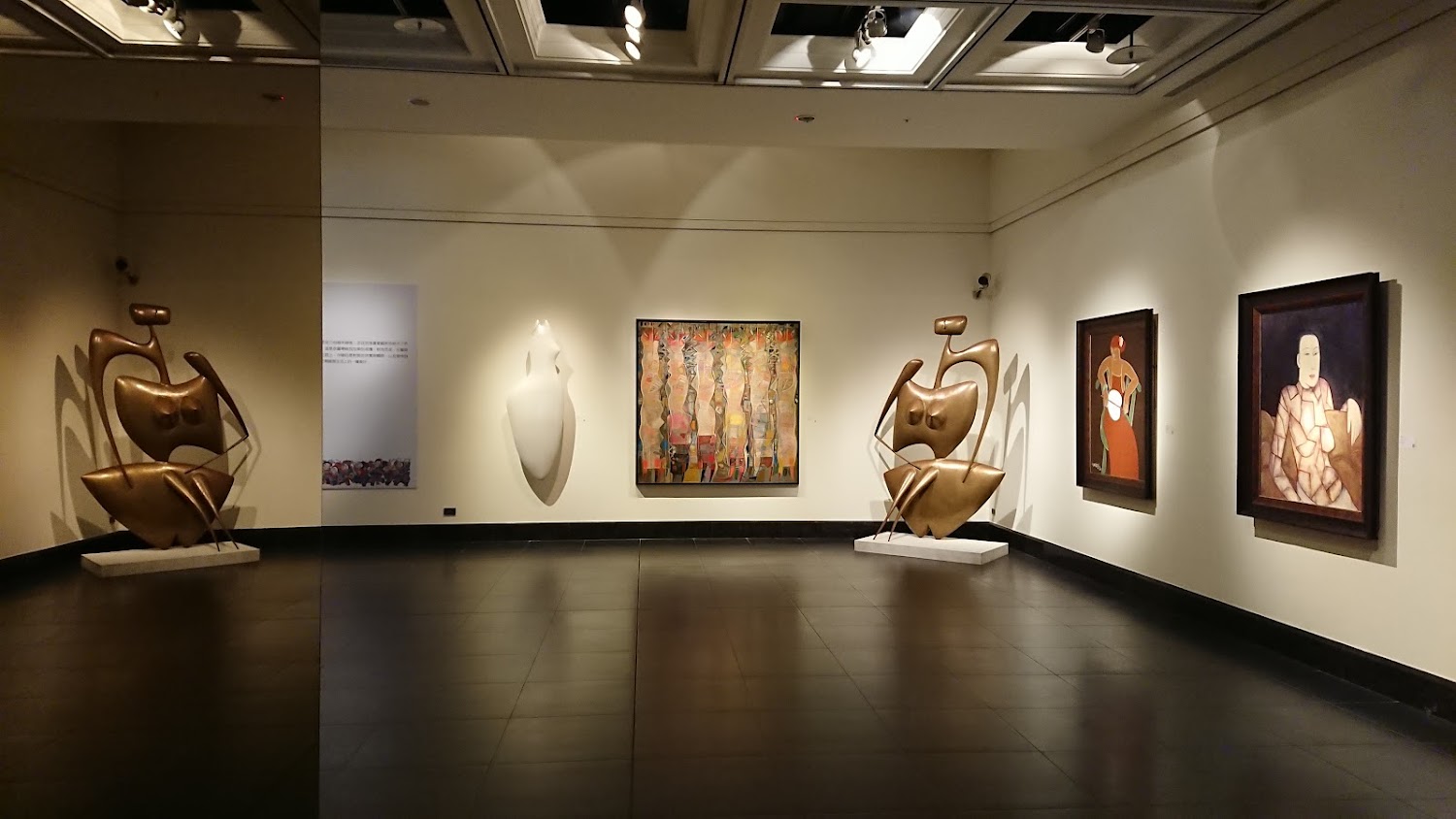 寬敞明亮的展廳，牆上有多幅畫作與大型雕塑