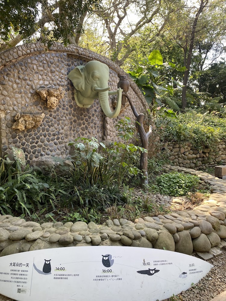 石牆上有大象頭雕塑與貓頭鷹解說牌