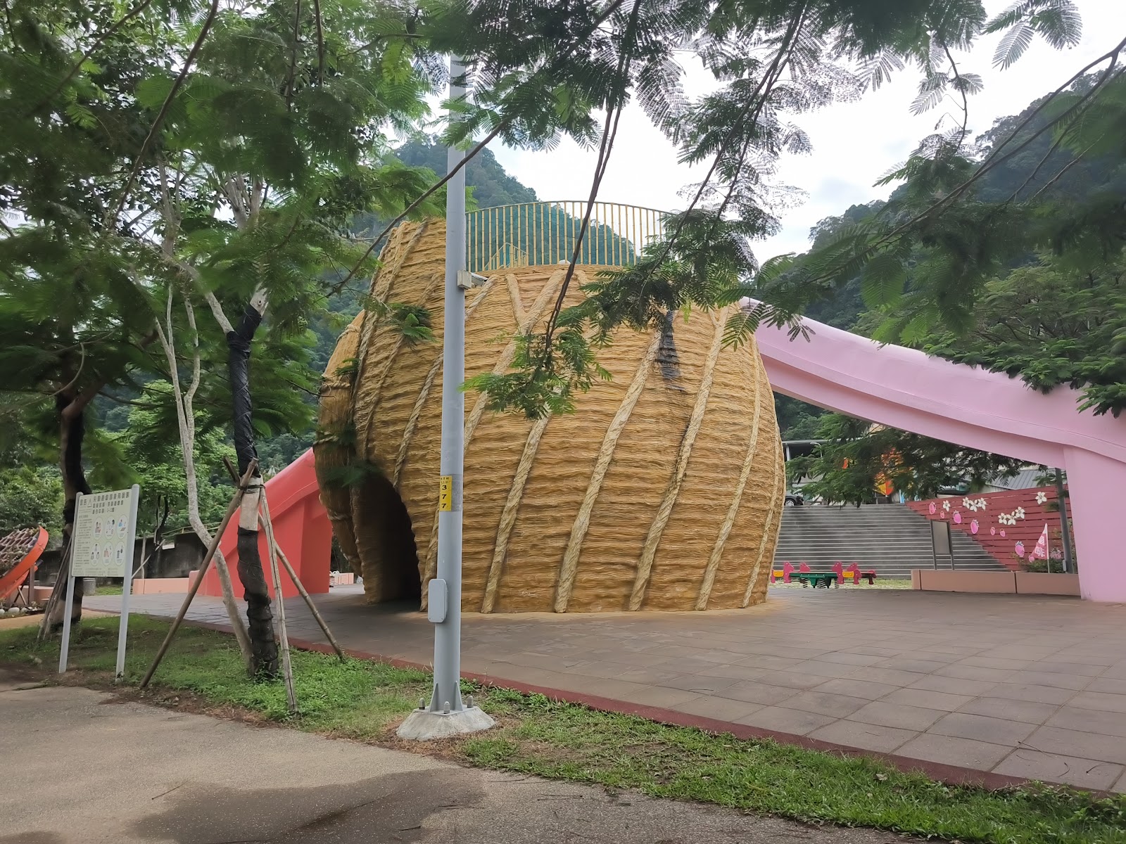 汶水老街大型稻草球裝置藝術，可穿越隧道入口，粉色展廳背景，山景綠樹
