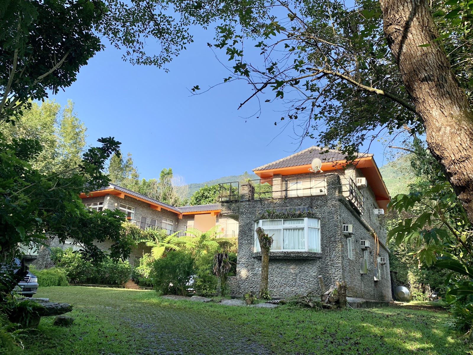 花蓮觀光糖廠橘色屋頂石造建築，翠綠庭園與山景背景