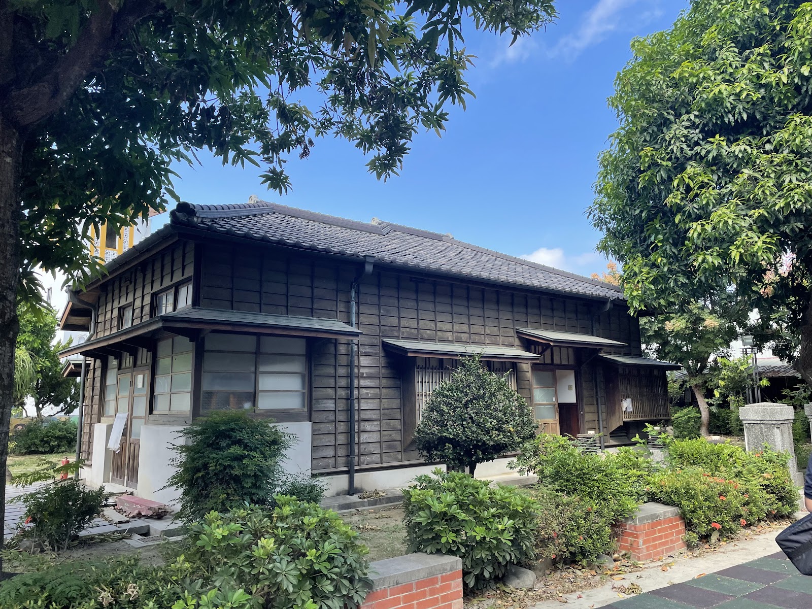 二林蔗農事件紀念館外觀，深褐色木造日式建築，黑色瓦片屋頂，藍天背景