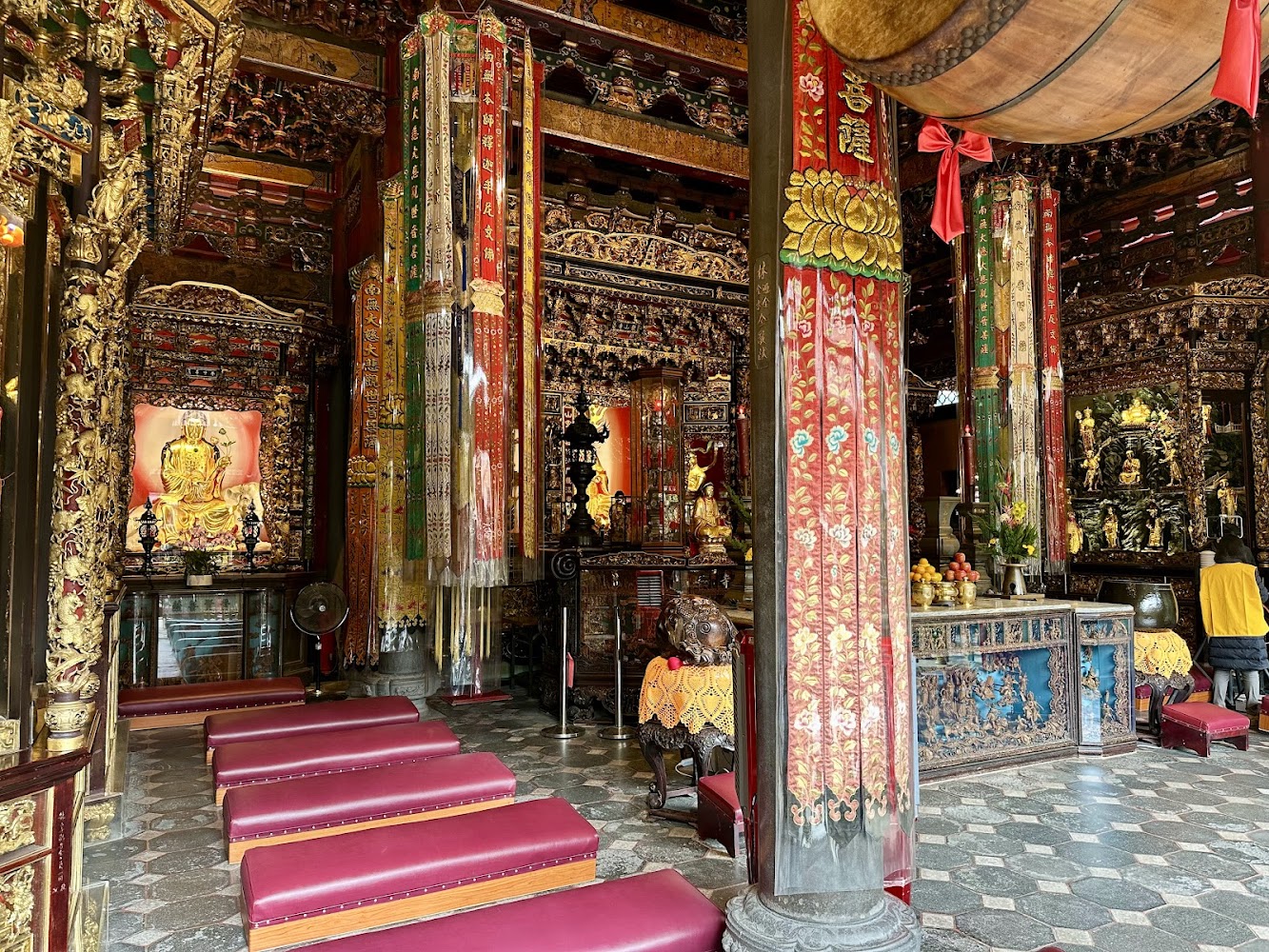 龍山寺內部供桌、佛像與雕刻柱樑，宗教氣氛莊嚴