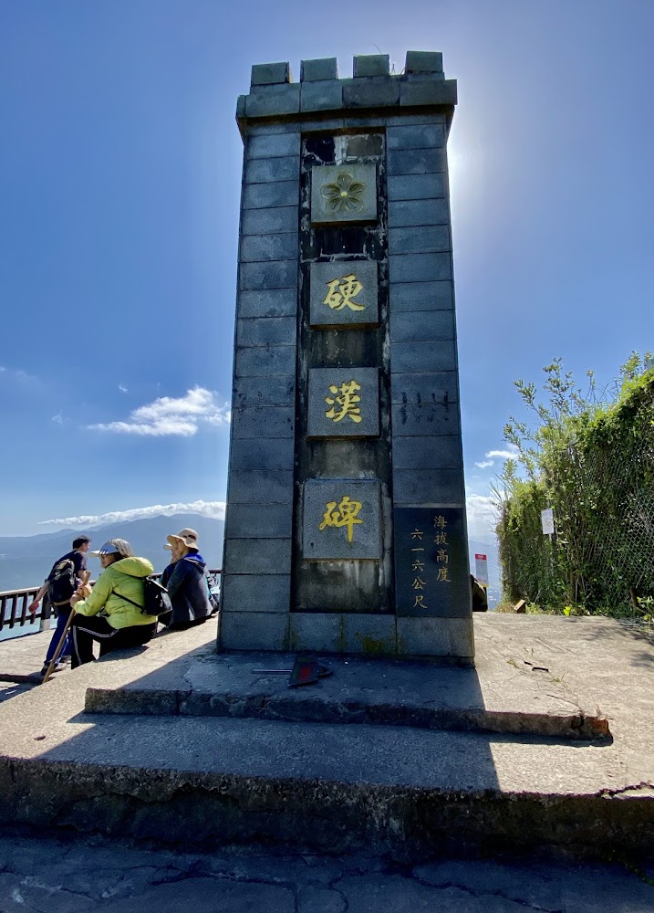 寫有硬漢碑的大型石碑，旁邊有山友休息
