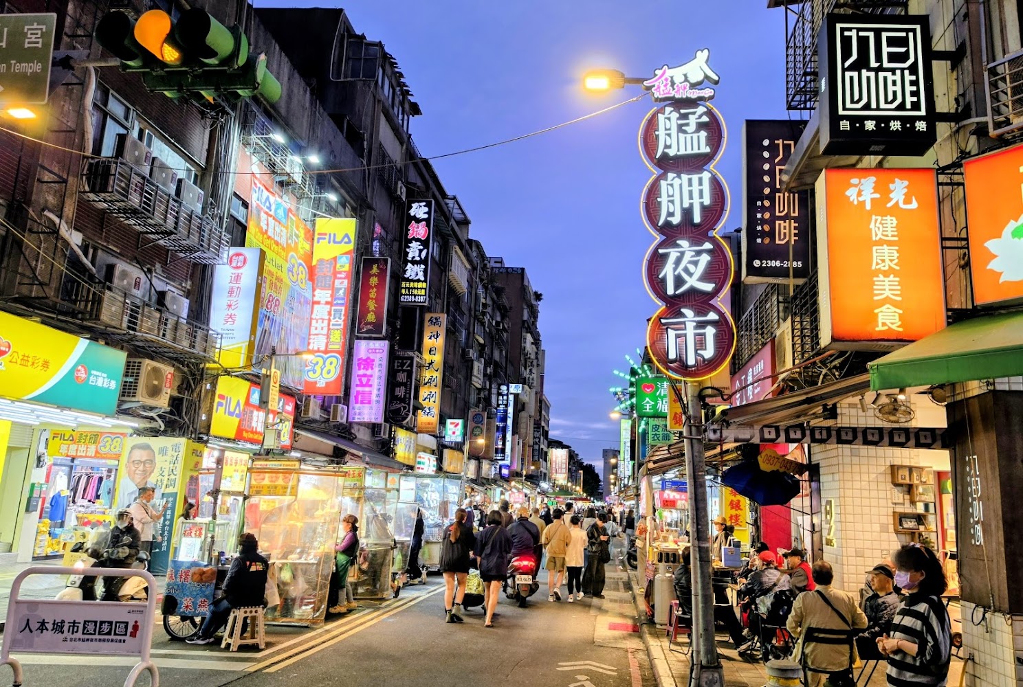 艋舺夜市街景，兩旁有豆花仙草冰與各式小吃攤
