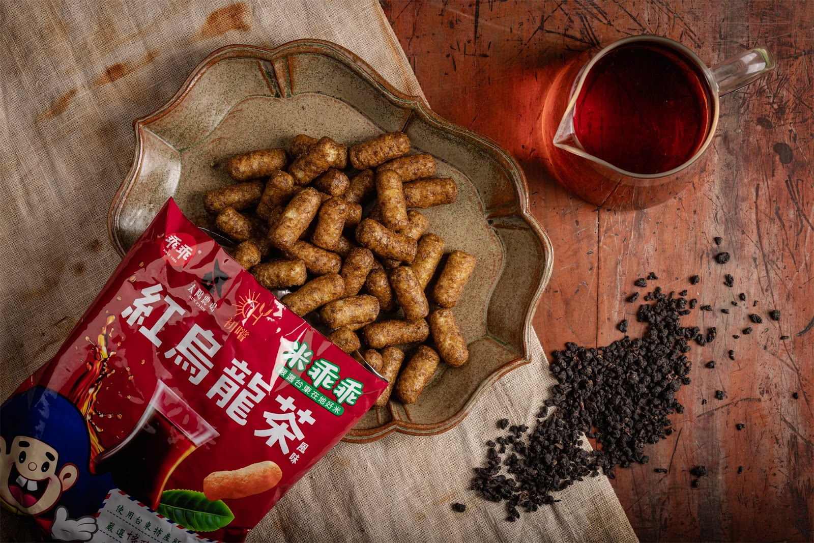 博雅齋鹿野紅烏龍茶商品,紅色包裝袋搭配陶製茶盤散落茶葉與茶杯