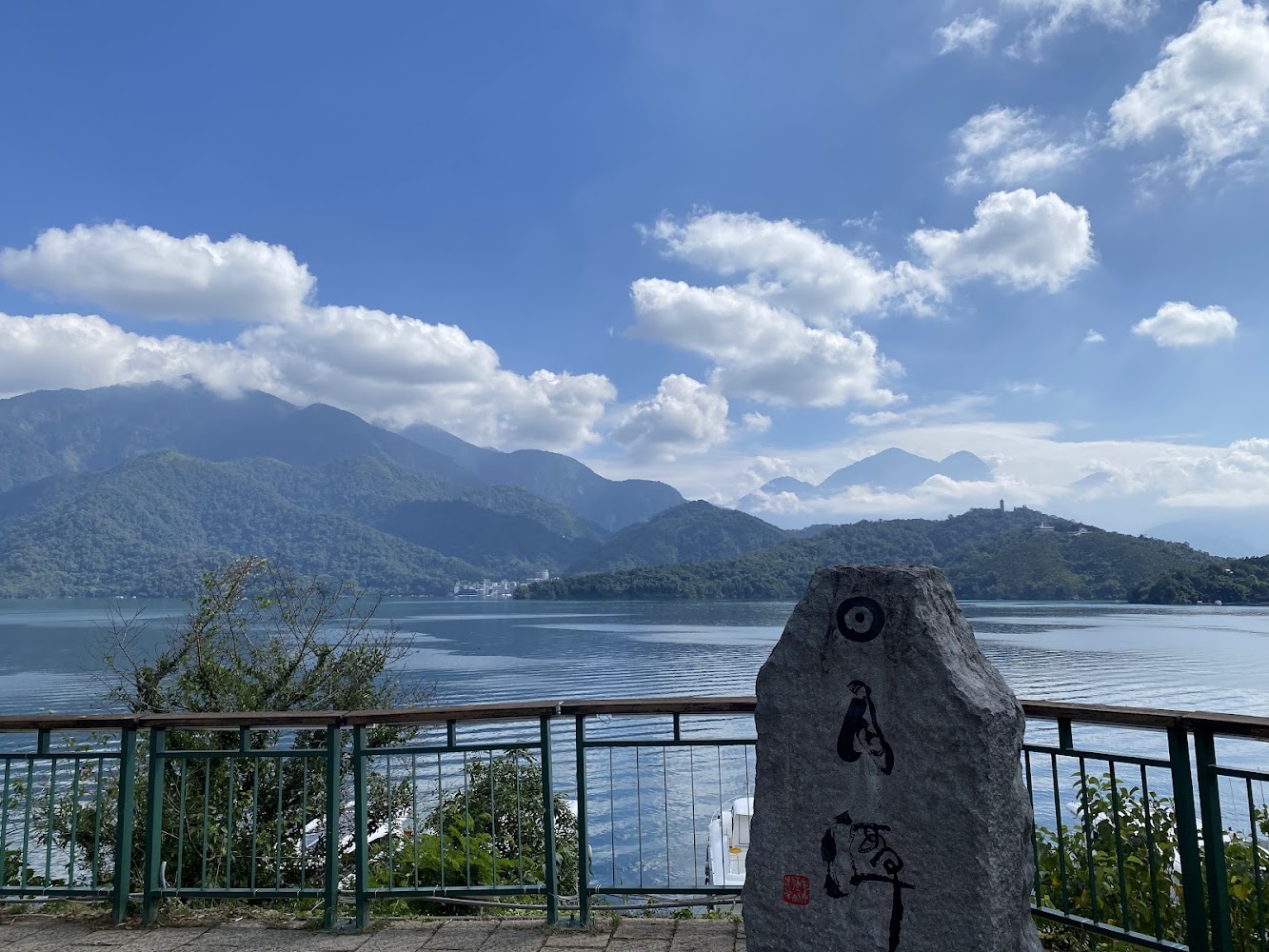 湖邊刻有書法字樣石碑與遠方山景藍天