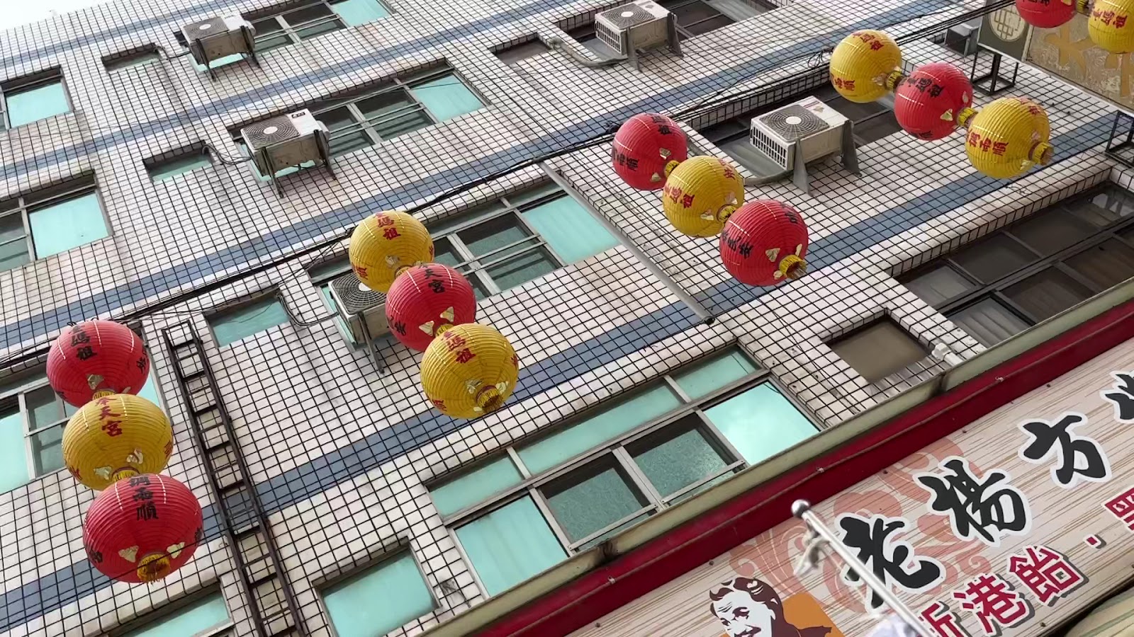 新港奉天宮周邊街道仰拍，紅黃燈籠高掛，節慶氣氛濃厚
