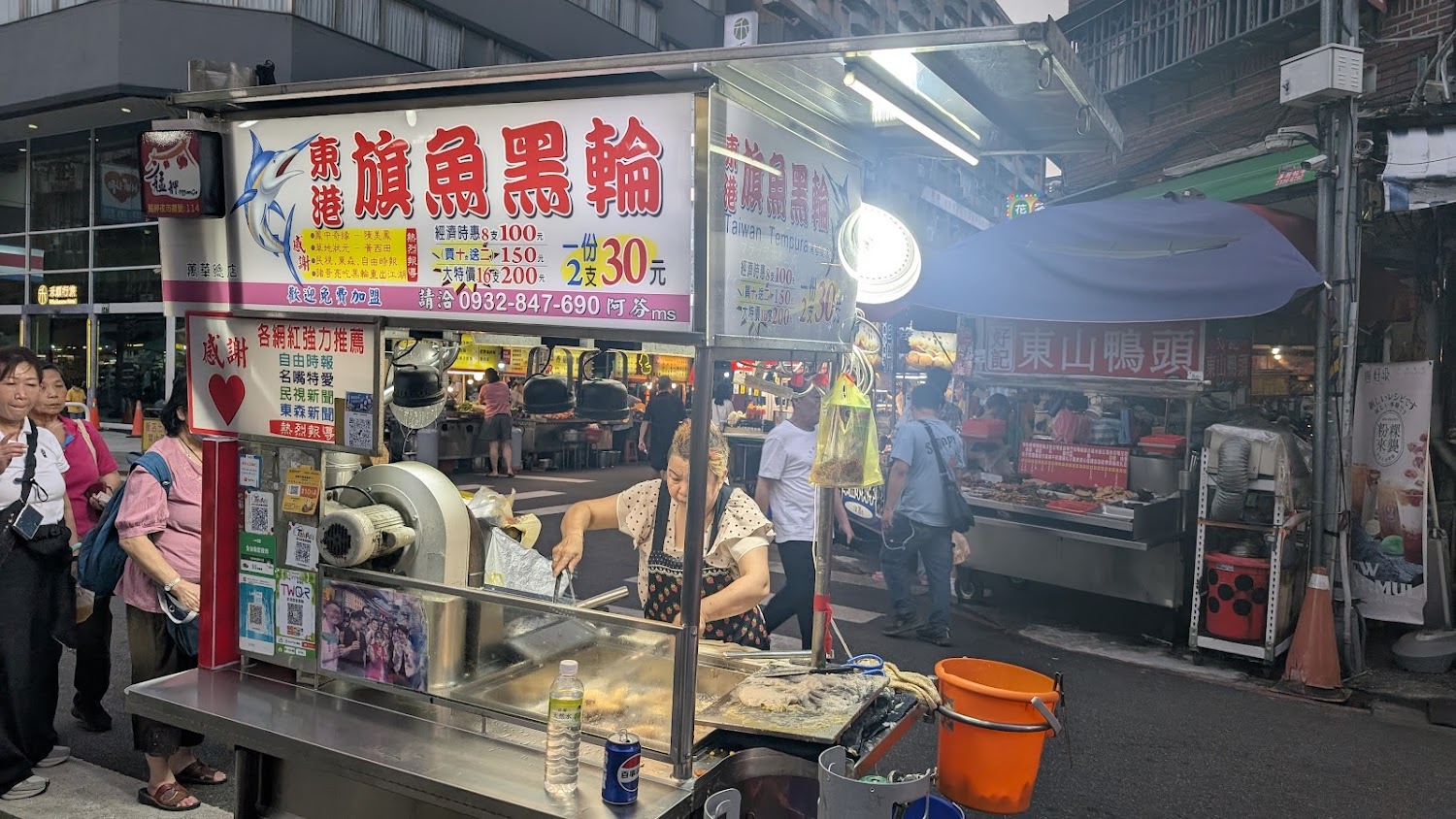 艋舺夜市東港旗魚黑輪攤位，招牌清楚，客人排隊購買