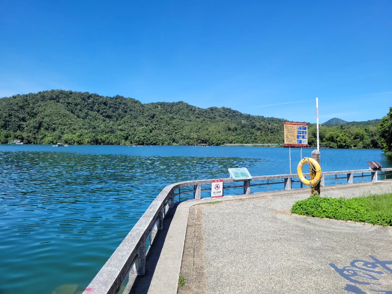湖邊欄杆救生圈對岸森林山丘晴朗天空