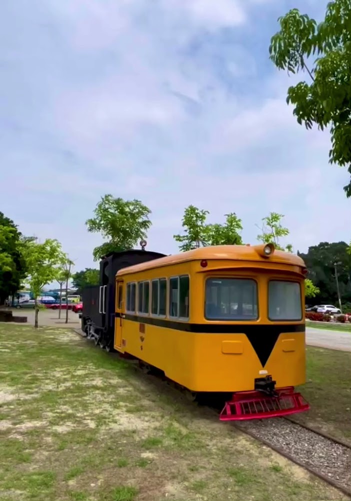 蒜頭糖廠園區內黃色復古列車停靠於戶外鐵道上。