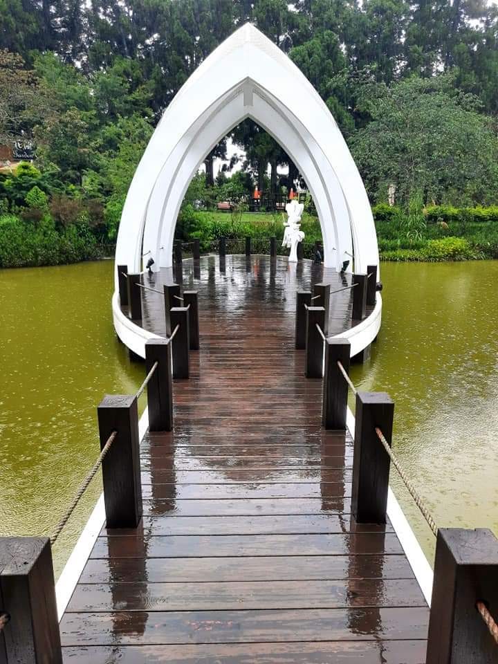 湖上的木橋，橋盡頭有白色拱型建築裝置和雕塑