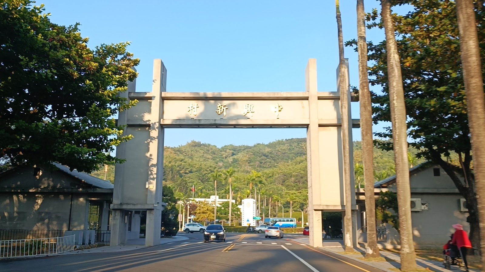 中興新村牌樓夕陽角度,車輛穿越拱門,後方綠色山巒