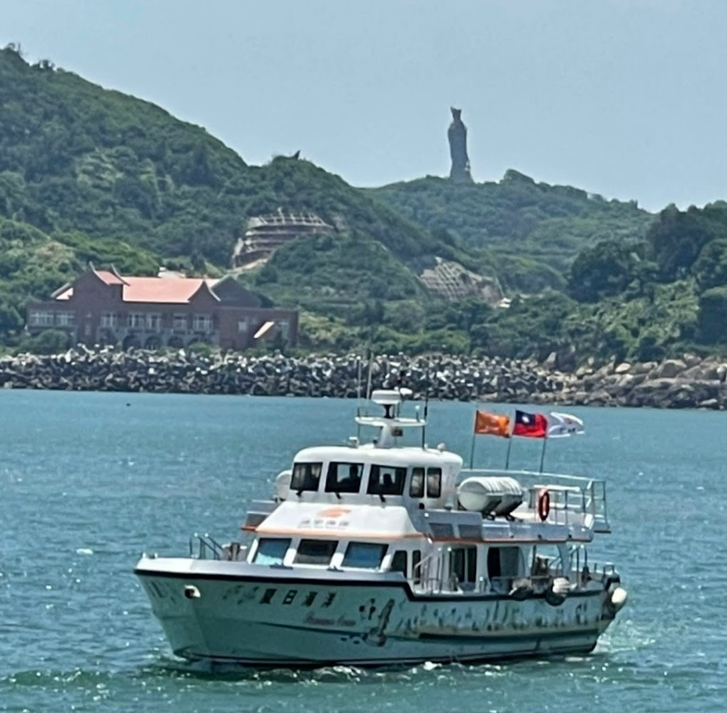 海上船隻與山坡上媽祖巨像