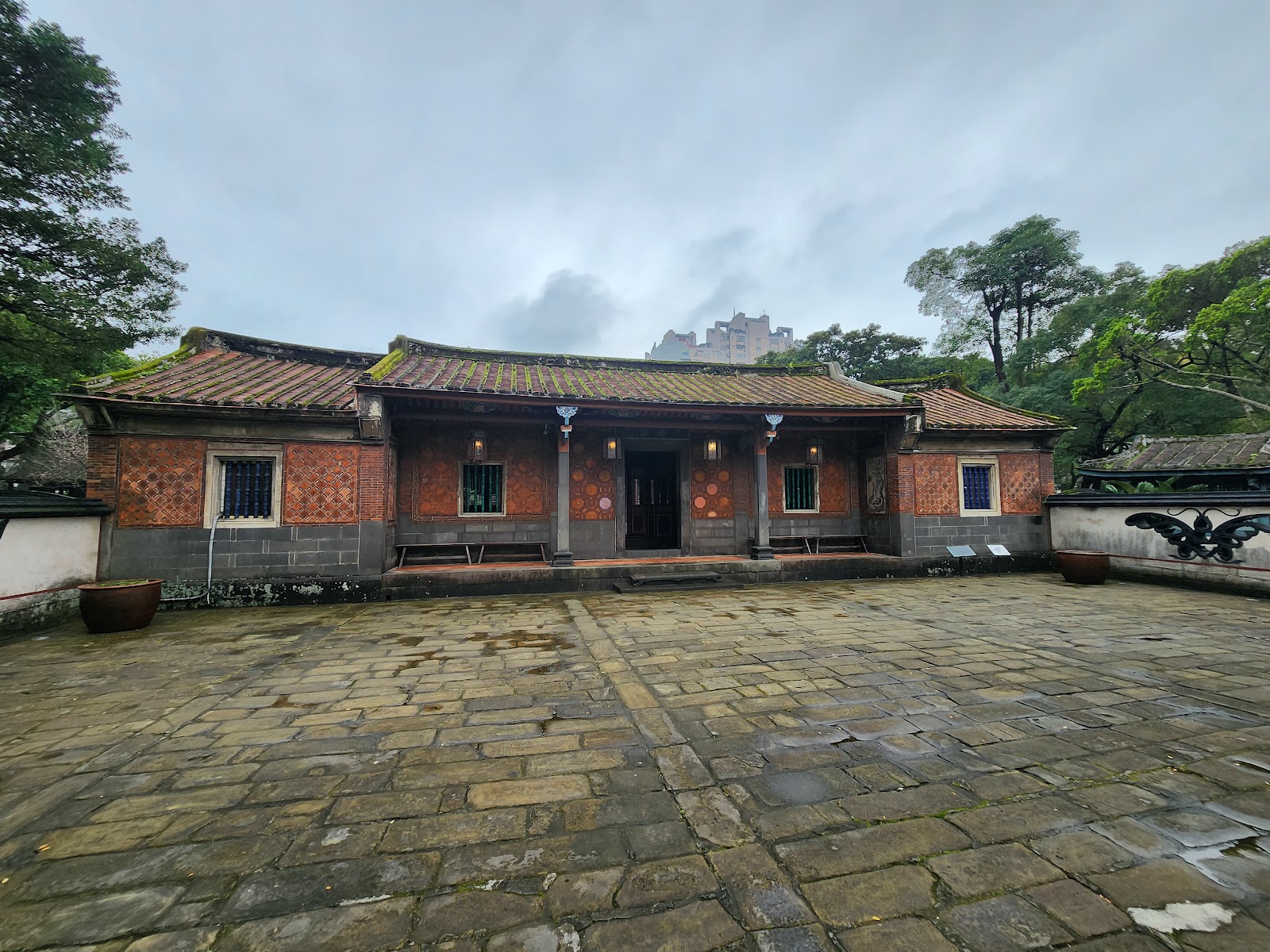三落大厝閩式建築正面，磚紅色外牆，翹脊屋頂，石板庭院