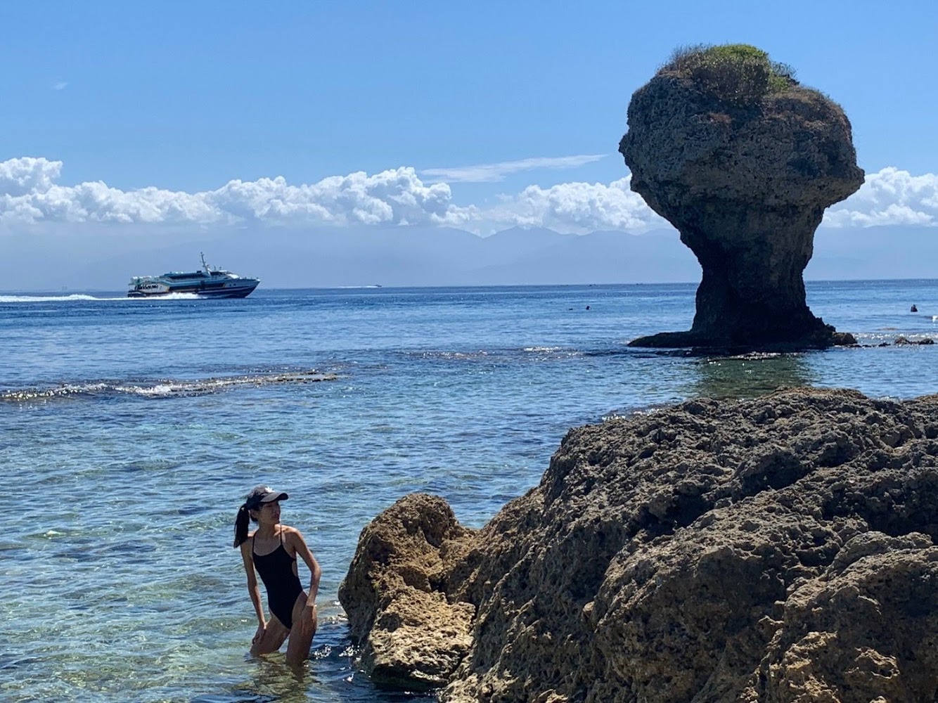 女子站在清澈海水中遠望花瓶岩