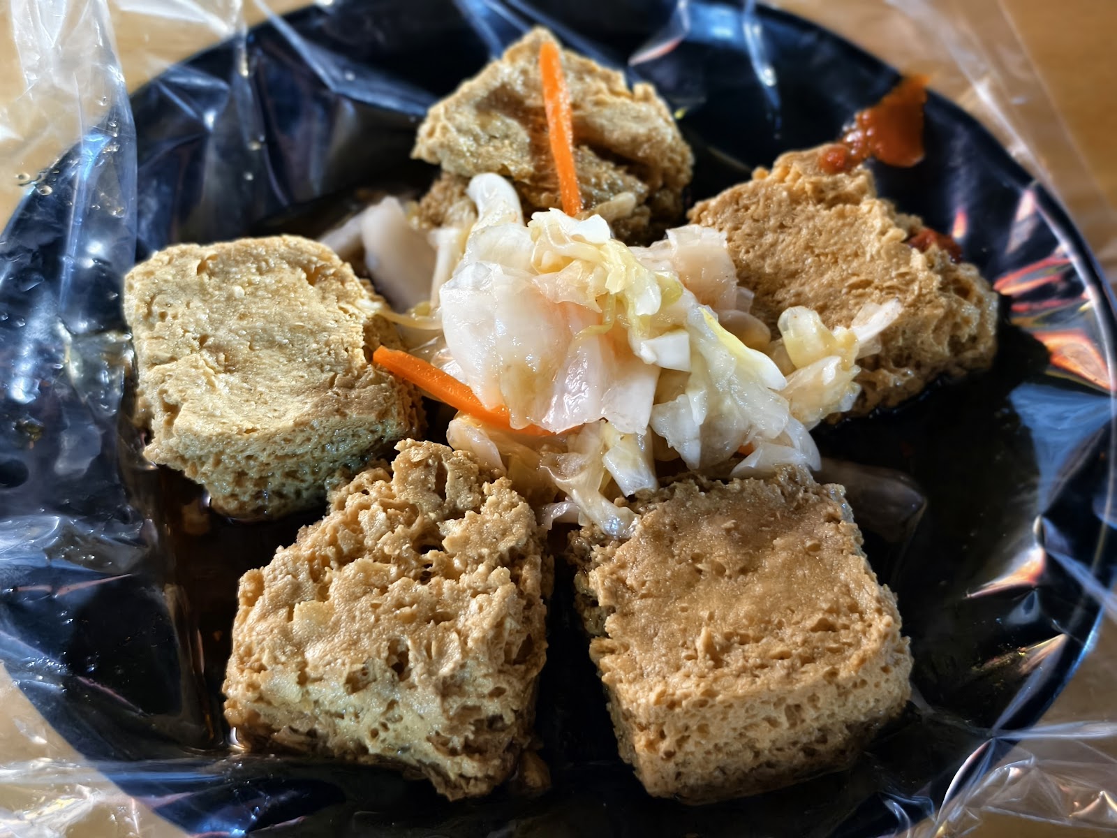 台南大東夜市炸臭豆腐特寫，黑盤盛放金黃炸豆腐配酸菜胡蘿蔔絲