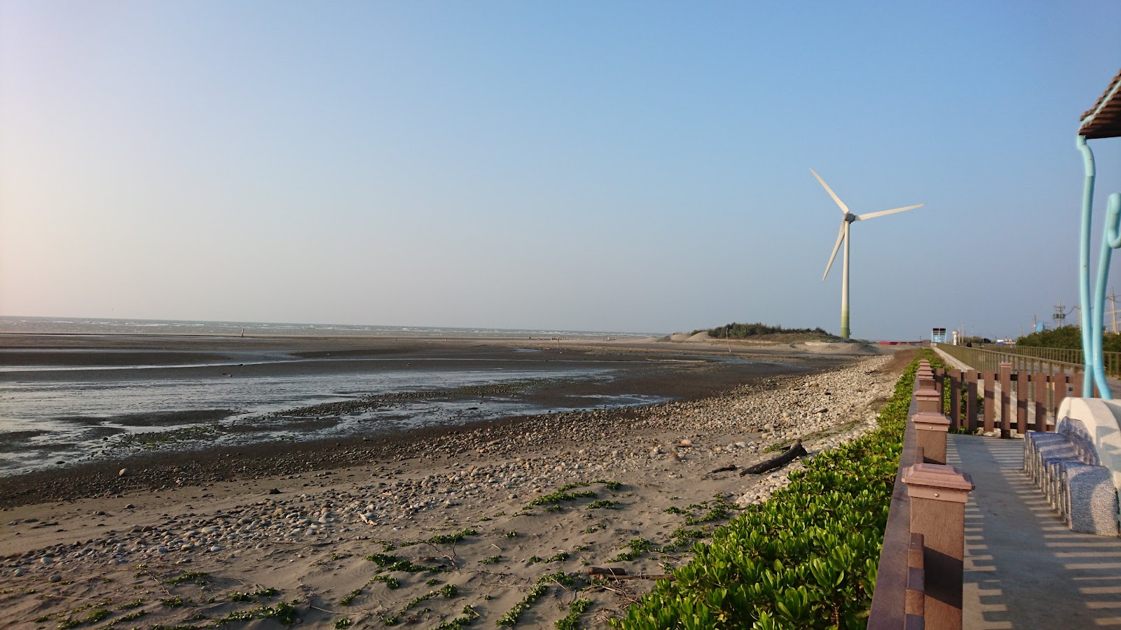 台中大安海水浴場退潮礫石灘全景,木柵欄步道與大型風車入鏡