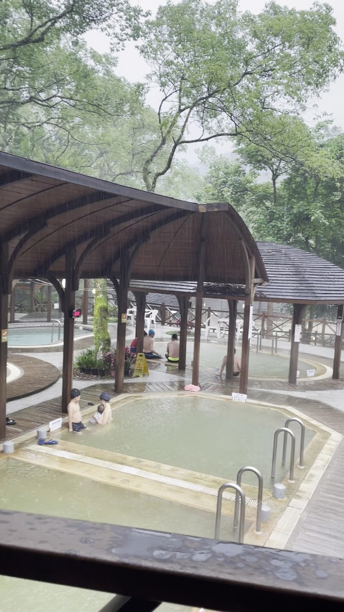 湧泉露天風呂白天木造涼亭下圓形溫泉池