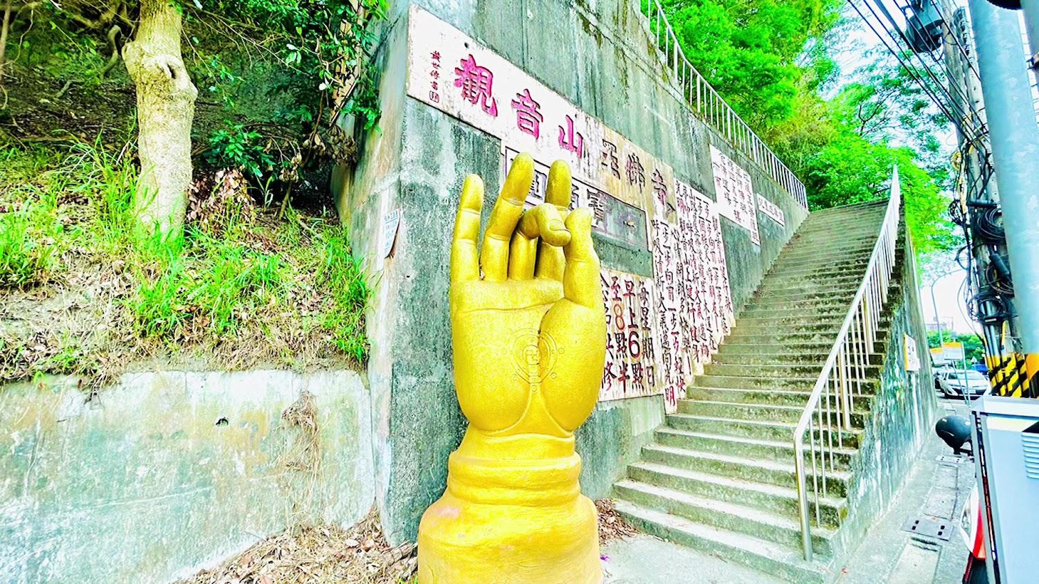 金色佛手雕像與階梯，後方有中文牆面