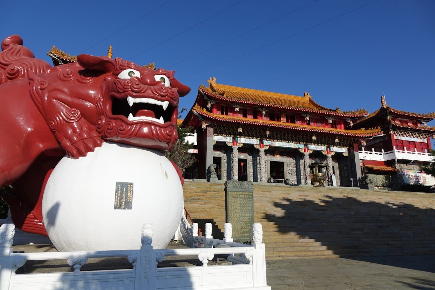 中國傳統寺廟建築前方紅色石獅雕像踩著大球