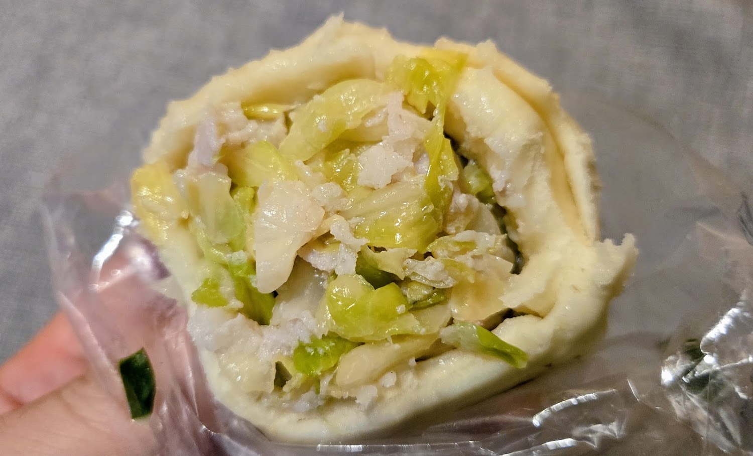 手拿咬開的包子可見高麗菜與絞肉內餡