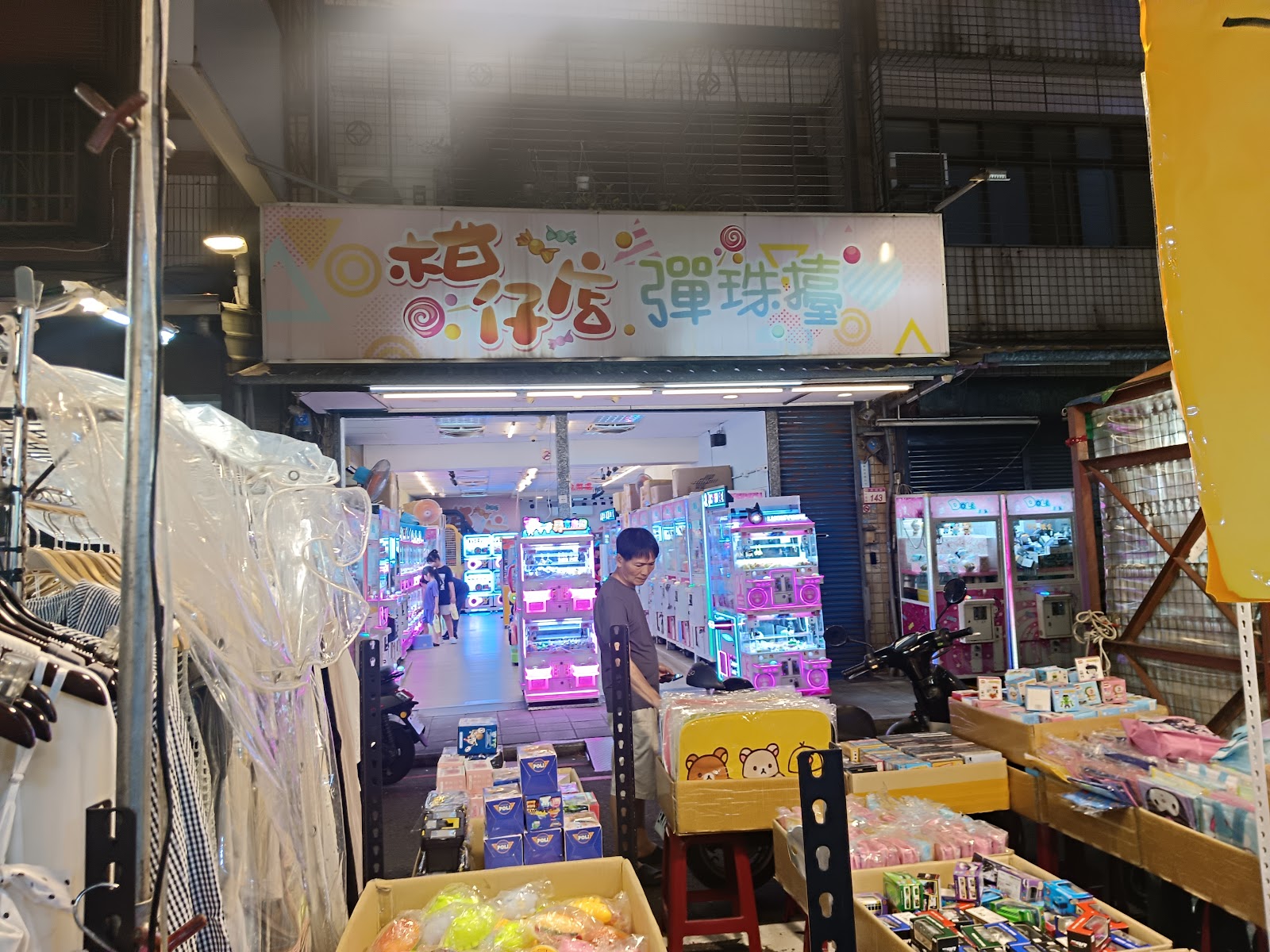 小哥仔店彈珠堂，霓虹招牌，店內抓娃娃機燈光閃爍