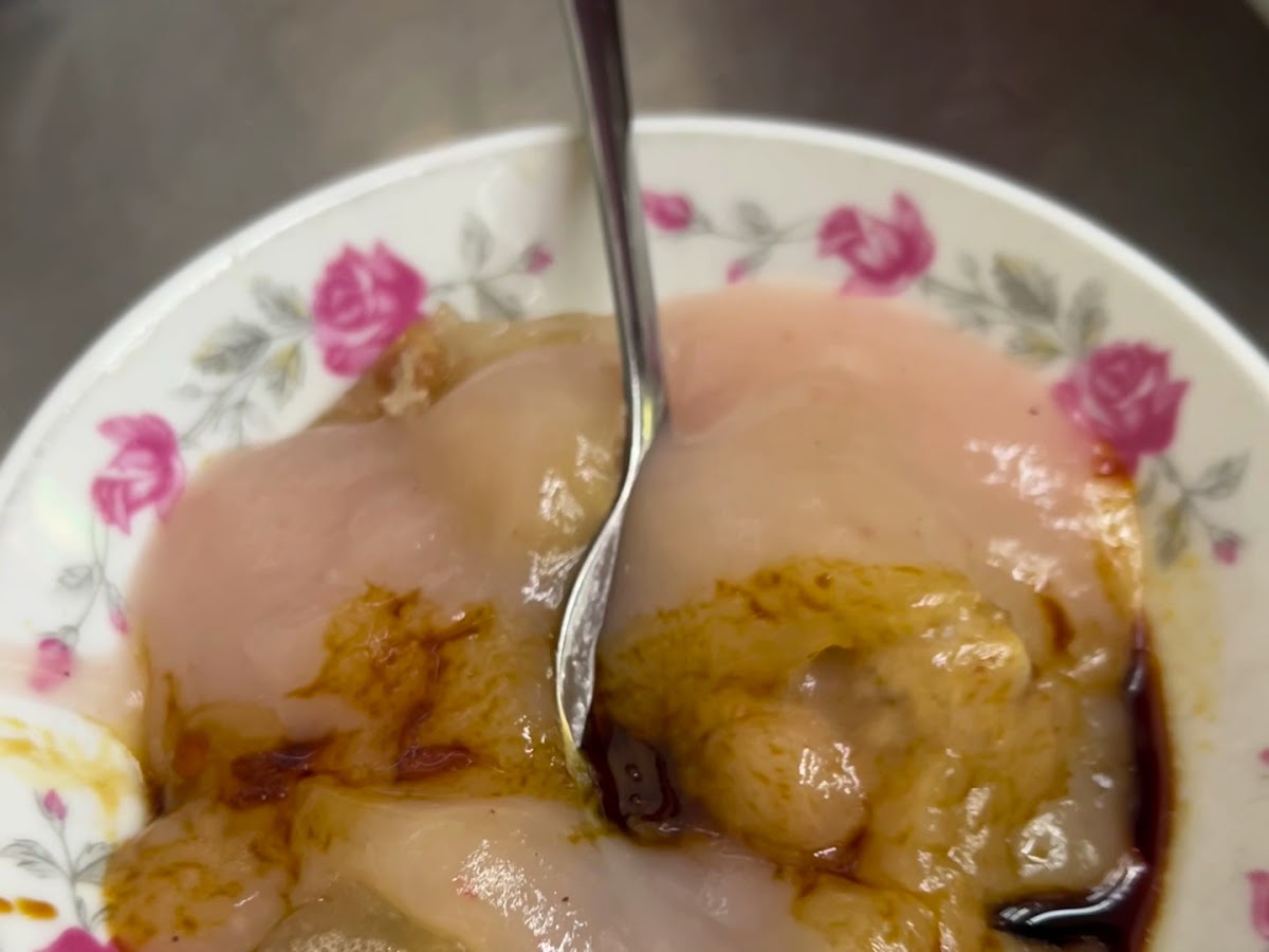 豐原肉丸近距特寫,玫瑰花紋碗中醬汁濃郁,湯匙插入準備享用