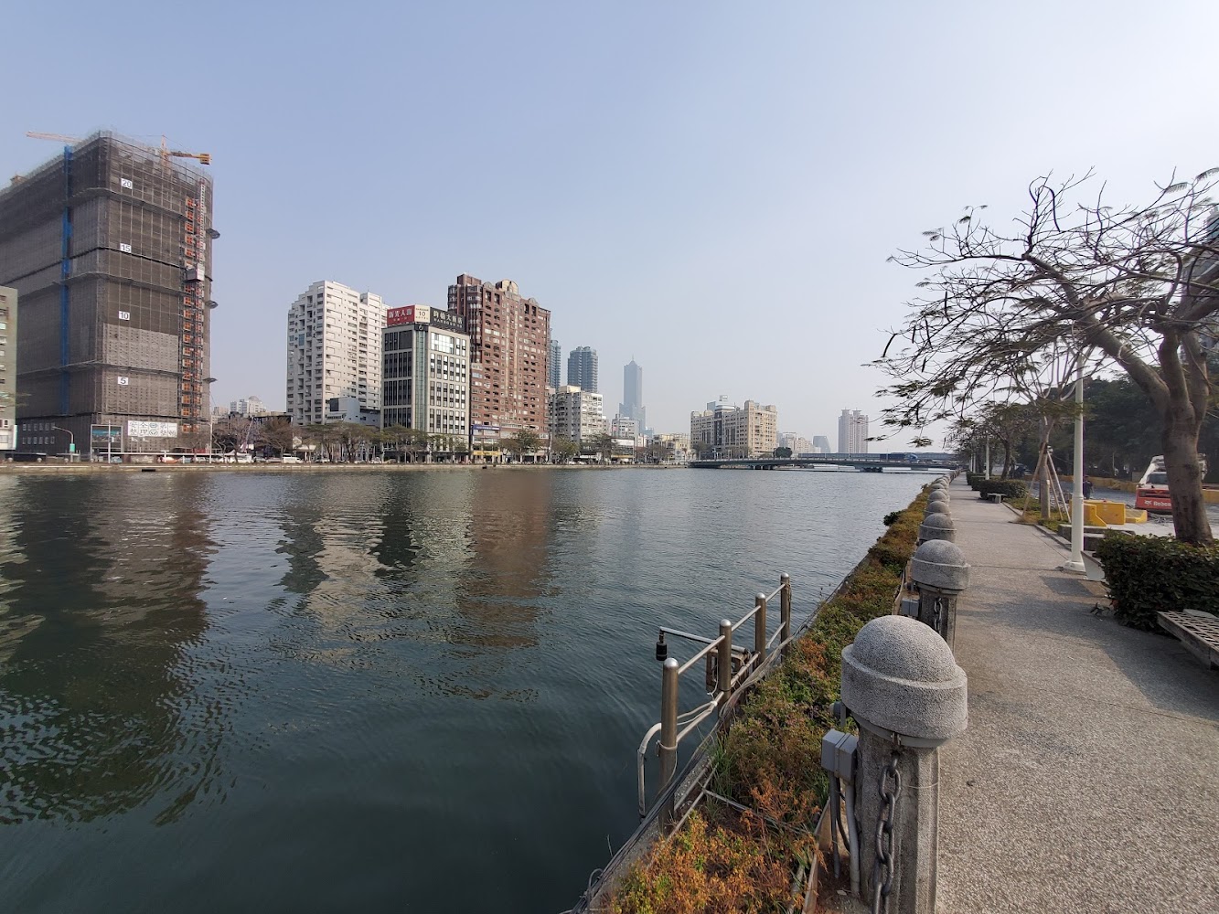 高雄河流步道欄杆樹木與都市建築風景