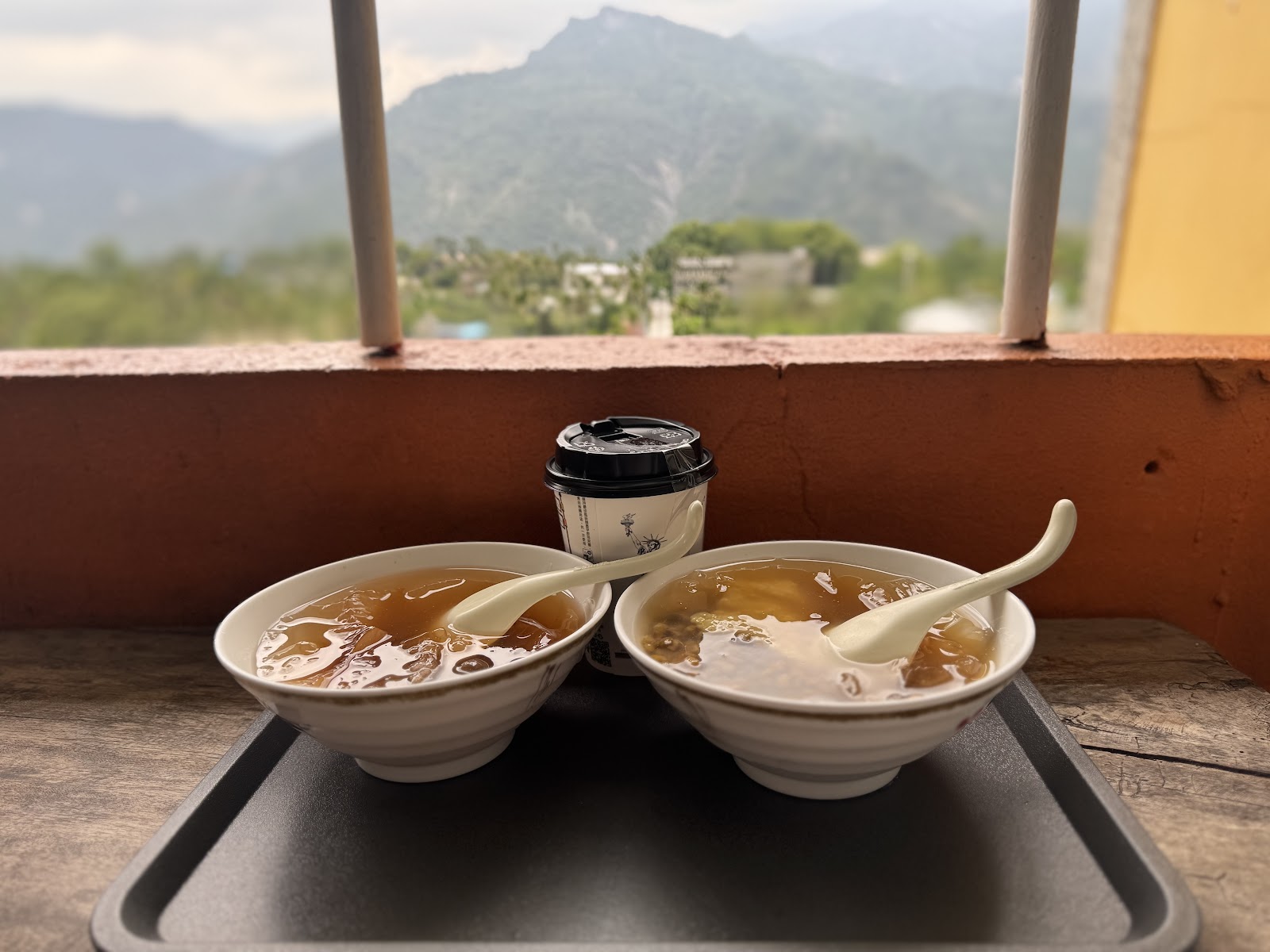 兩碗愛玉冰擺放在山景前,畫面清爽療癒